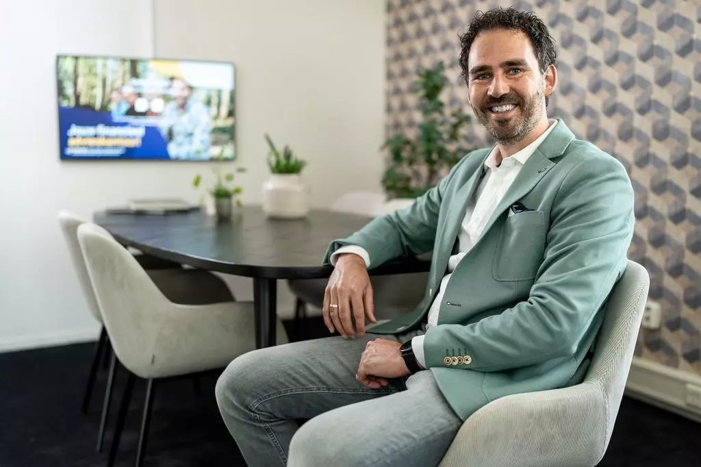 Financieel adviseur zit op een stoel met zijn arm leunend op een zwarte tafel in een kantoor